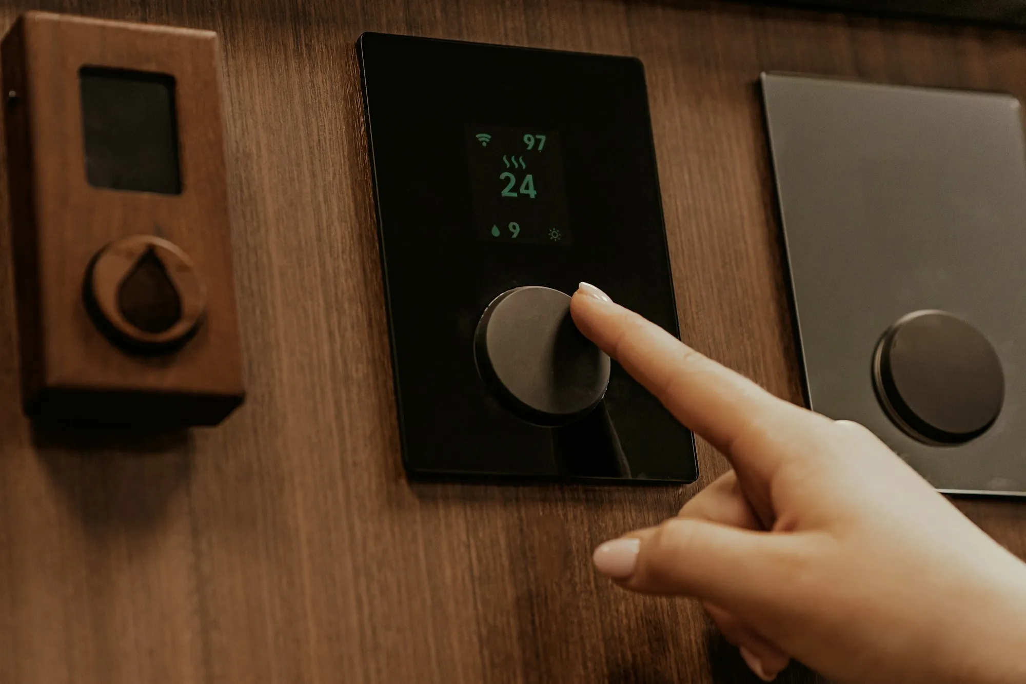 Finger pressing a smart thermostat on a wood wall